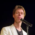 Martin Schneider Artikelbild mit Retro-Mikrofon auf Bühne in hochwertigem Editorial-Stil