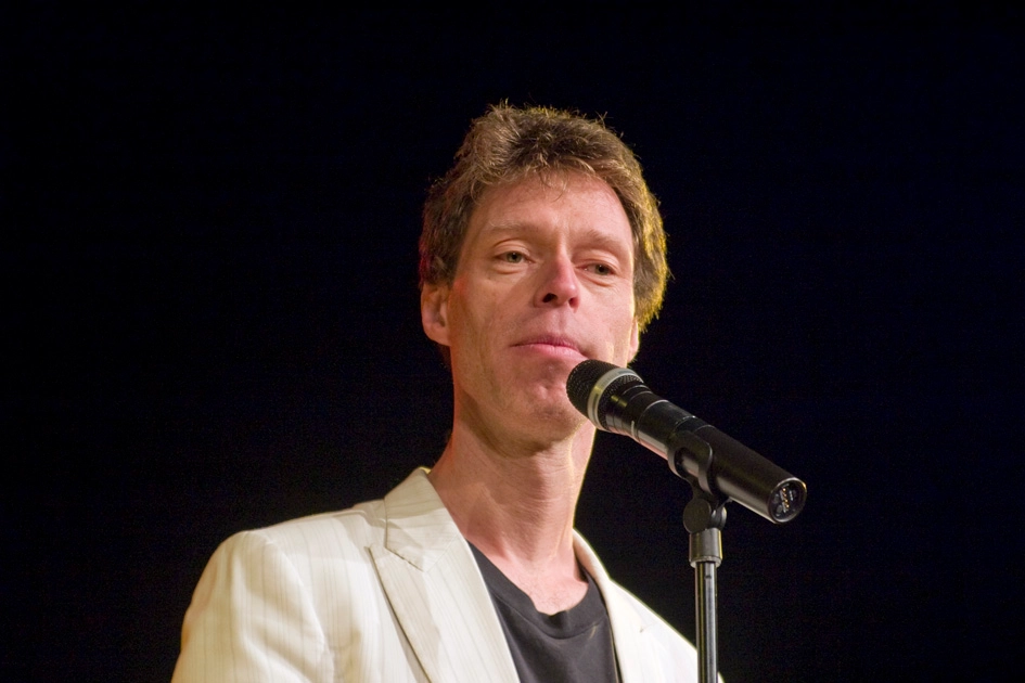 Martin Schneider Artikelbild mit Retro-Mikrofon auf Bühne in hochwertigem Editorial-Stil